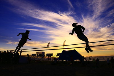 Low angle view of silhouette man jumping against sky