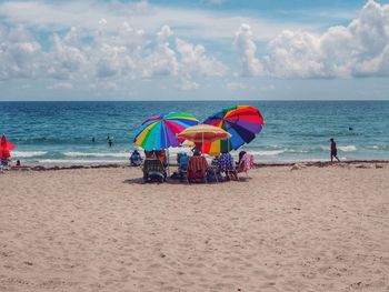 Chairs and parasols at beach against sky