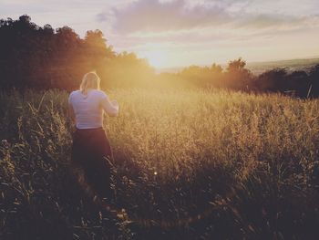 Rear view of woman standing on field against sky