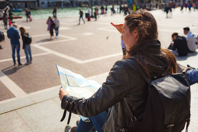 Dark haired girl looking at venetian paper map sitting on santa luchia square