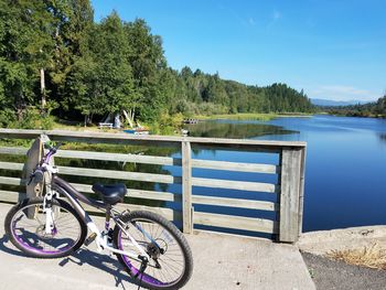 Bicycle by lake against blue sky