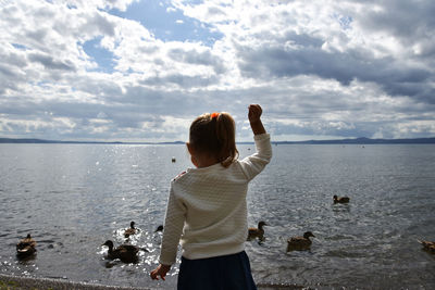 Rear view of woman standing on beach against sky