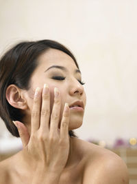 Close-up of shirtless woman touching cheek at spa