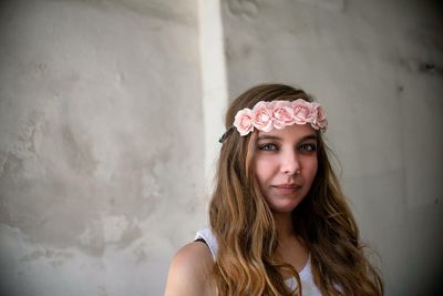 Portrait of beautiful young woman against wall