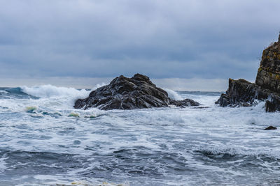 Scenic view of rocks in sea against sky