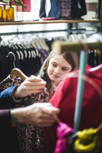 Cute girl looking at dress while shopping in boutique