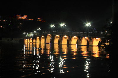 Illuminated bridge against sky at night