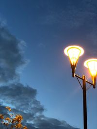 Low angle view of illuminated street light against sky