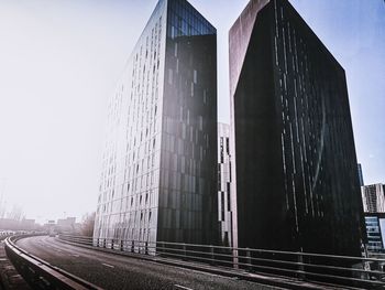 Road by modern buildings against sky