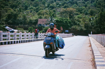 Rear view of man riding motorcycle on street