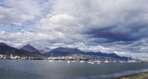 Boats in sea against cloudy sky