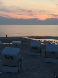 Information sign on beach against sky during sunset