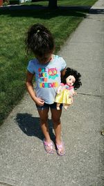 High angle view of girl with doll standing on footpath