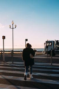 Rear view of woman on road against sky during sunrise