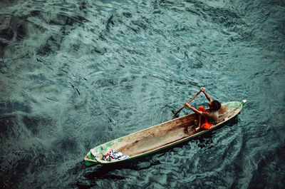 High angle view of boy rowing rowboat in river