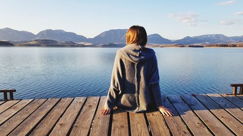 Rear view of woman looking at lake against sky