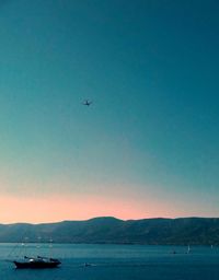 Airplane flying over sea against clear sky