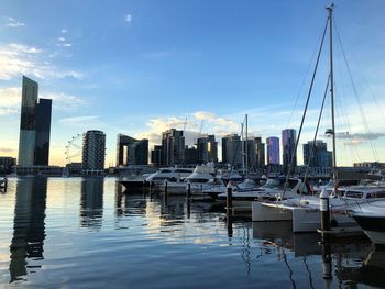 Sailboats moored in harbor against buildings in city