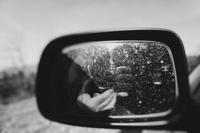 Reflection of man photographing on side-view mirror