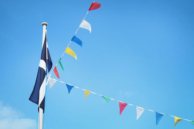 Low angle view of flags hanging against blue sky