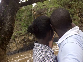 Rear view of couple kissing against trees