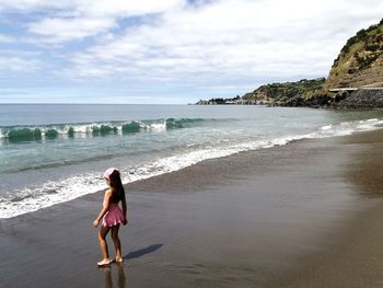 Full length of woman standing on beach against sky