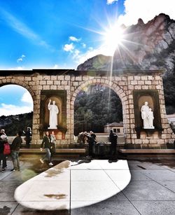 People at historical building on sunny day
