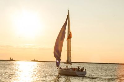 Sailboat sailing on sea against sky during sunset