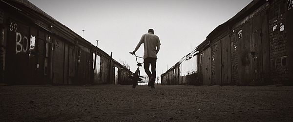 Rear view of shirtless man walking on bridge