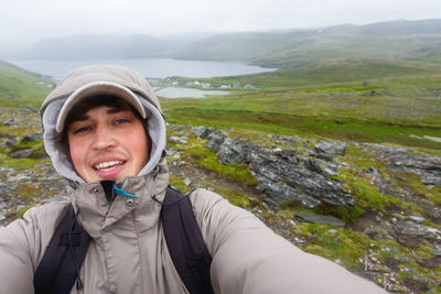 Tourist man making selfie on hill near skarsvag. landmark on lofoten islands. norway.