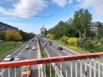 Vehicles on road against sky in city