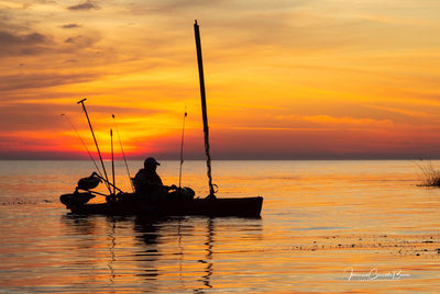 Silhouette people on sea against sky during sunset