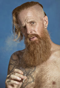 Portrait of shirtless man against blue background