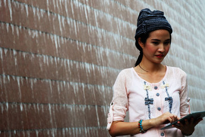 Woman using digital tablet against wall