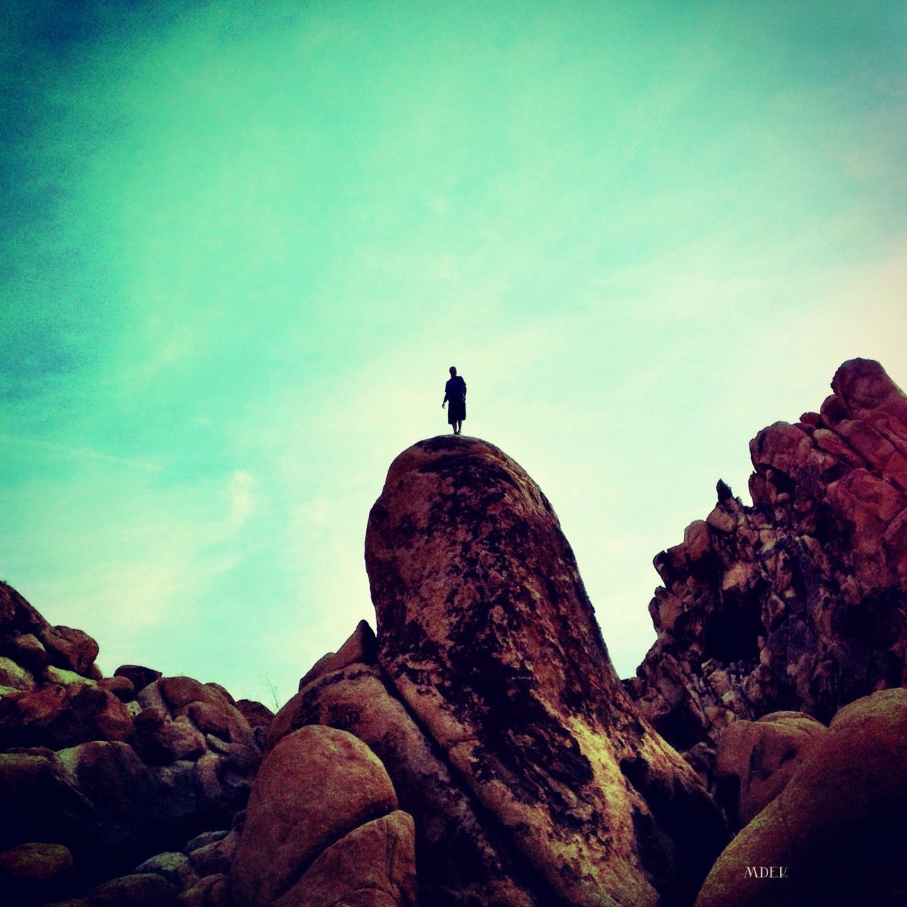 rock - object, sky, low angle view, bird, silhouette, one animal, tranquility, nature, rock, rock formation, beauty in nature, full length, tranquil scene, scenics, animal themes, copy space, blue, wildlife, animals in the wild, clear sky