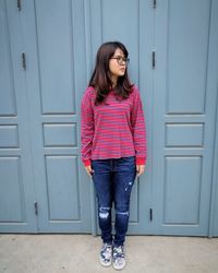 Woman looking away while standing against door