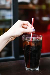 Cropped hand of woman holding drink at cafe