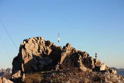 Low angle view of rocks against clear blue sky