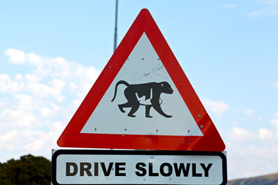 Close-up of road sign against sky