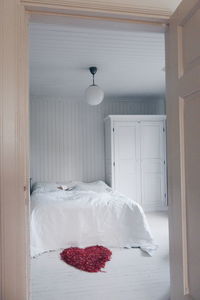 Rose petals in heart shape at bedroom seen through doorway