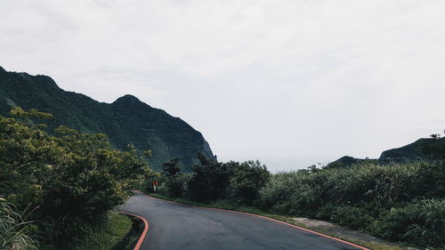 Road amidst trees against clear sky