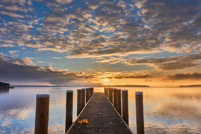 Pier over sea against sky during sunset