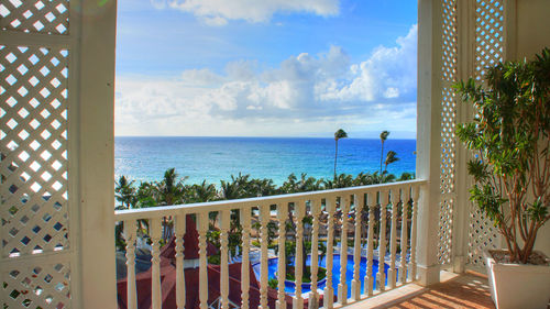 View of swimming pool by sea against sky seen from balcony