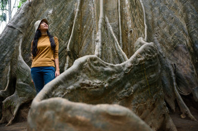 Low angle view of woman standing on rock in forest