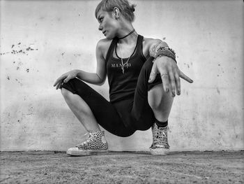 Young woman looking away while sitting on wall