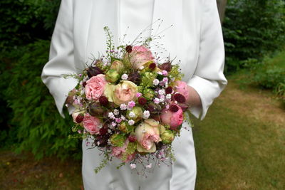 Midsection of bride holding bouquet