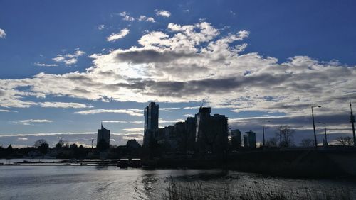 City at waterfront against cloudy sky