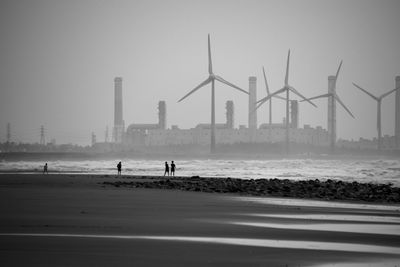 People on beach against sky in city