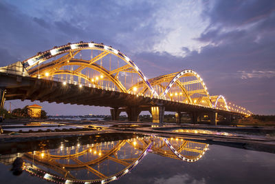 Illuminated bridge over river against sky at night