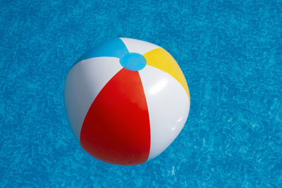 Inflatable beach ball afloat in swimming pool water on a sunny summer day